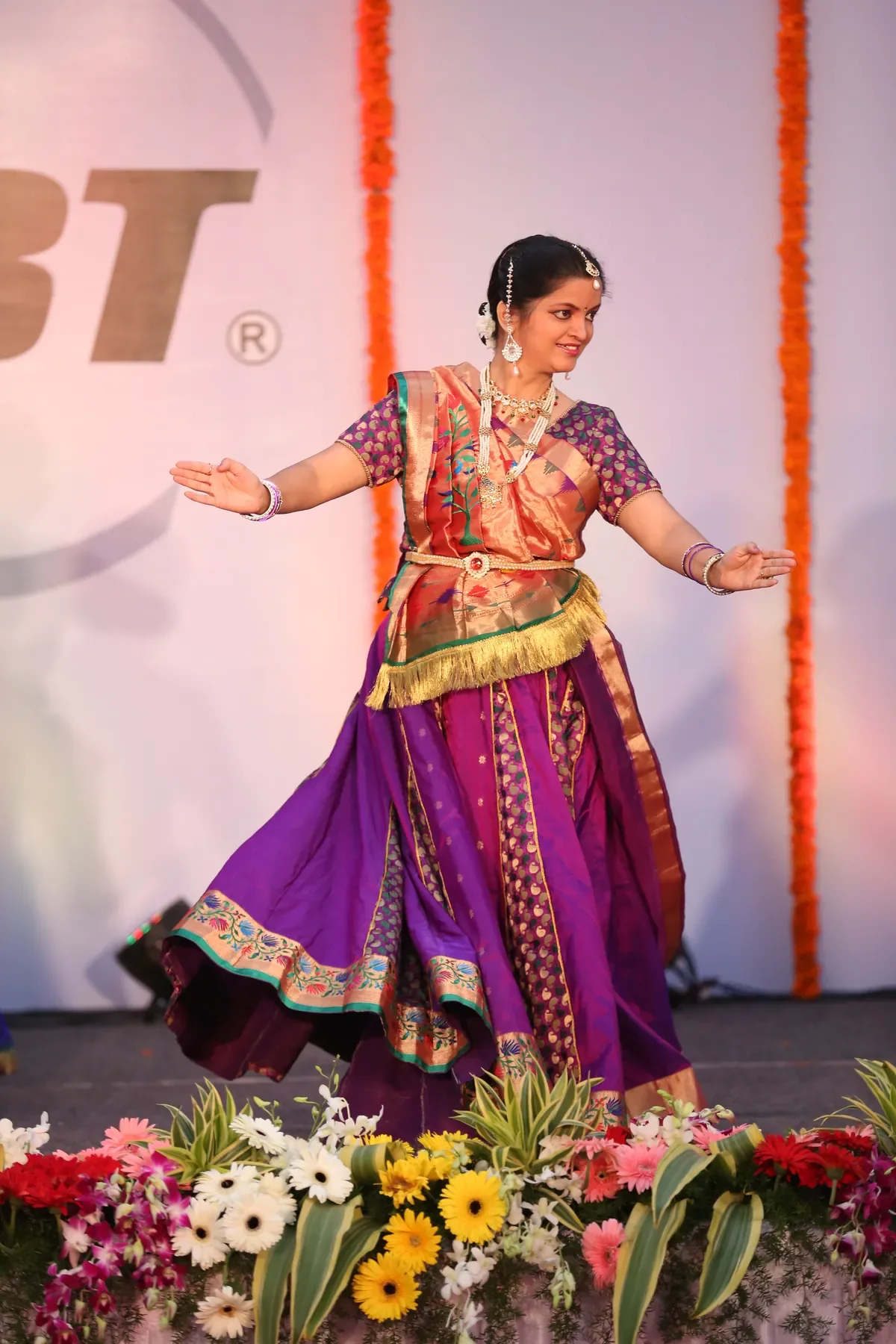 A dancer of Archana Nrityalaya turning a chakkar in purple and gold at a corporate function