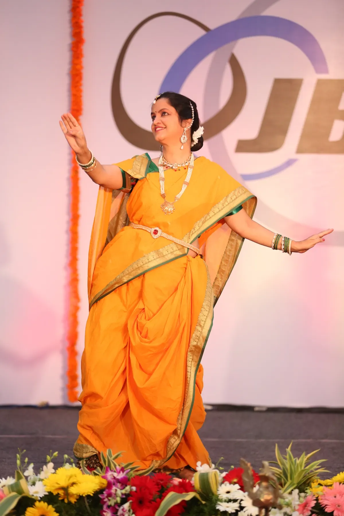 Guru Archana Patwardhan performing in a marigold nauvari sari at a corporate event in Pune