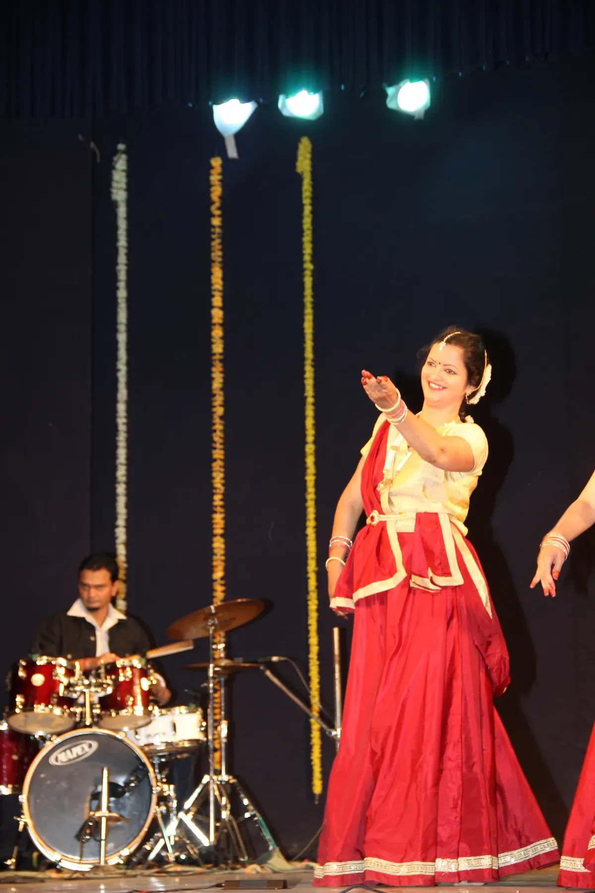 Guru Archana Patwardhan dancing to live percussion beside marigold garlands on a Pune stage