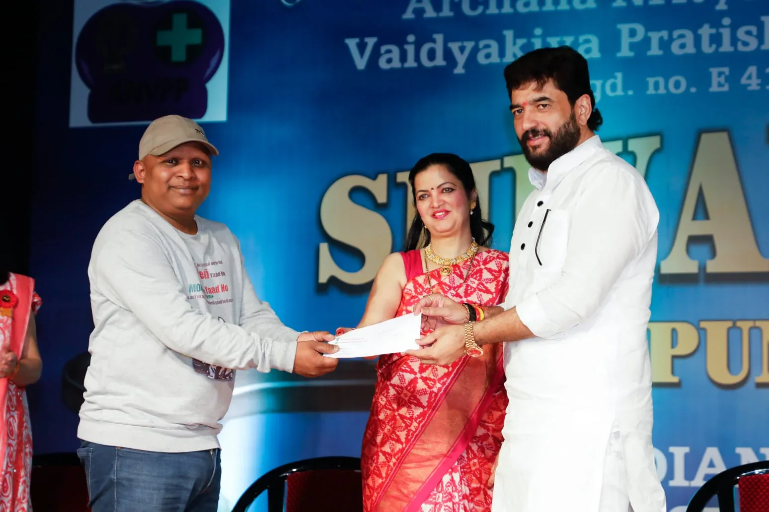Murlidhar Mohol and Guru Archana Patwardhan presenting financial support to a patient at ANVPP's 2024 event
