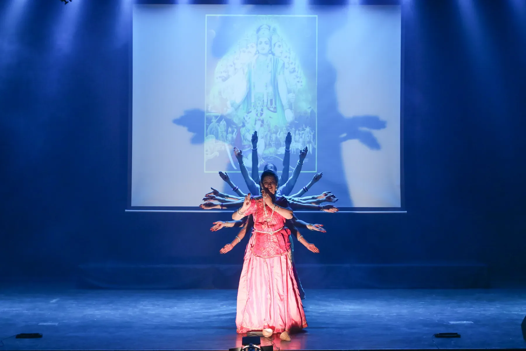 Dancers of Archana Nrityalaya forming the many-armed Vishwaroop tableau beneath a projected image of Vishnu
